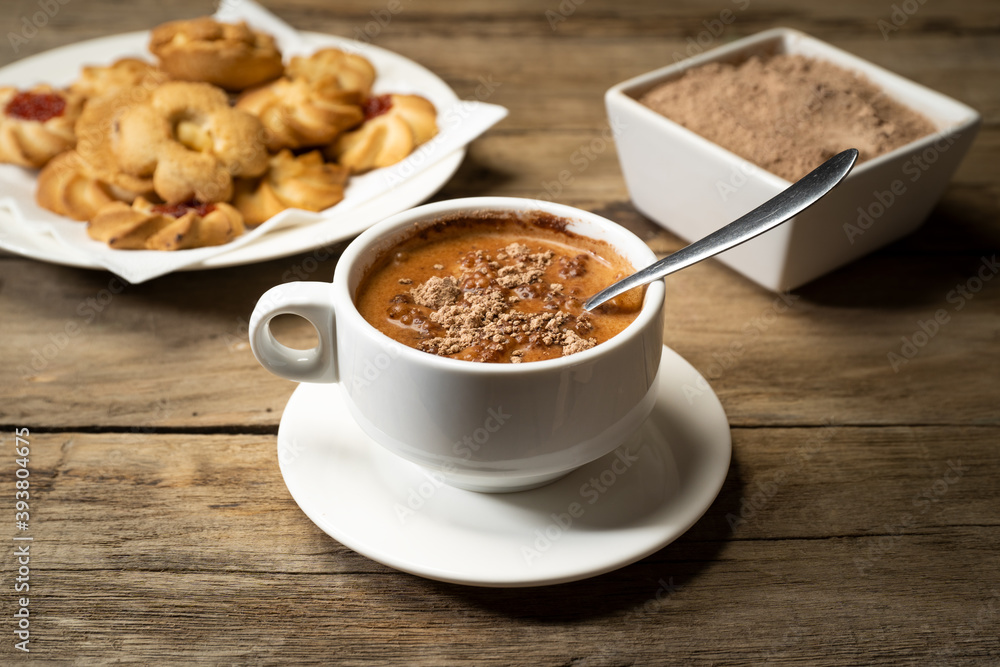 Cup of cocoa with lumps with pastes and cocoa powder on rustic table