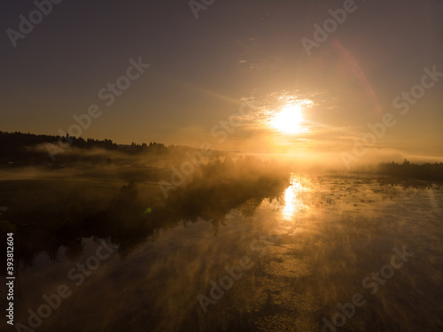 Aerial view of the foggy sunrise on the lake in forest with smoky sky. Fantastic landscape. Wallpaper design. Discover the world concept.