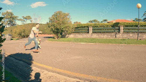 Labrador retriever breed dog runs behind his owner who is skating through the urbanization on a sunny morning