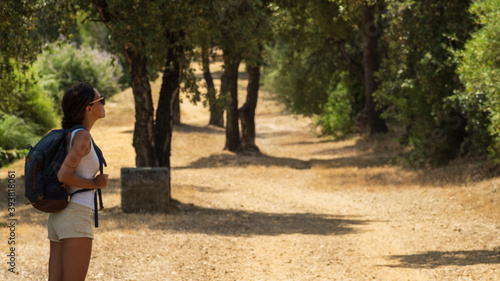 Backpack girl walking under trees in the summer