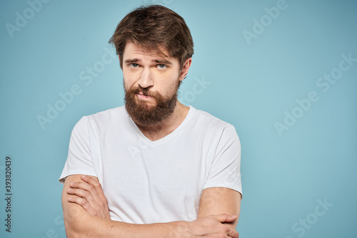 Man in white t-shirt lifestyle studio emotions facial expression blue isolated background © SHOTPRIME STUDIO