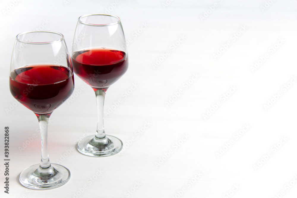 Two glasses of red wine on a white background and with a soft shadow. Side view. Copy space.