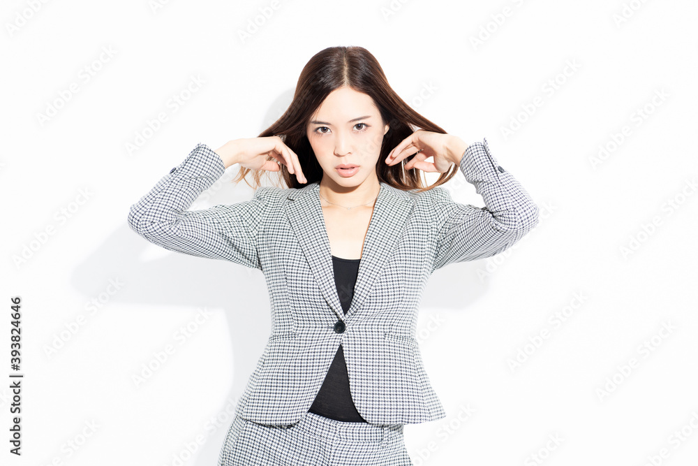 白い背景の前に立ってポーズをとる若いビジネスウーマン
