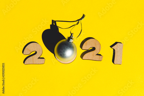 Numbers 2021 from wooden letters and christmas ball on a yellow background.