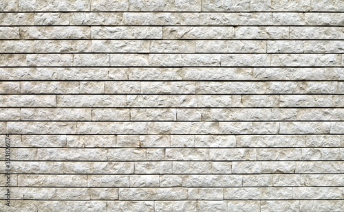 Stone wall made of white granite regular bricks. Background and texture 