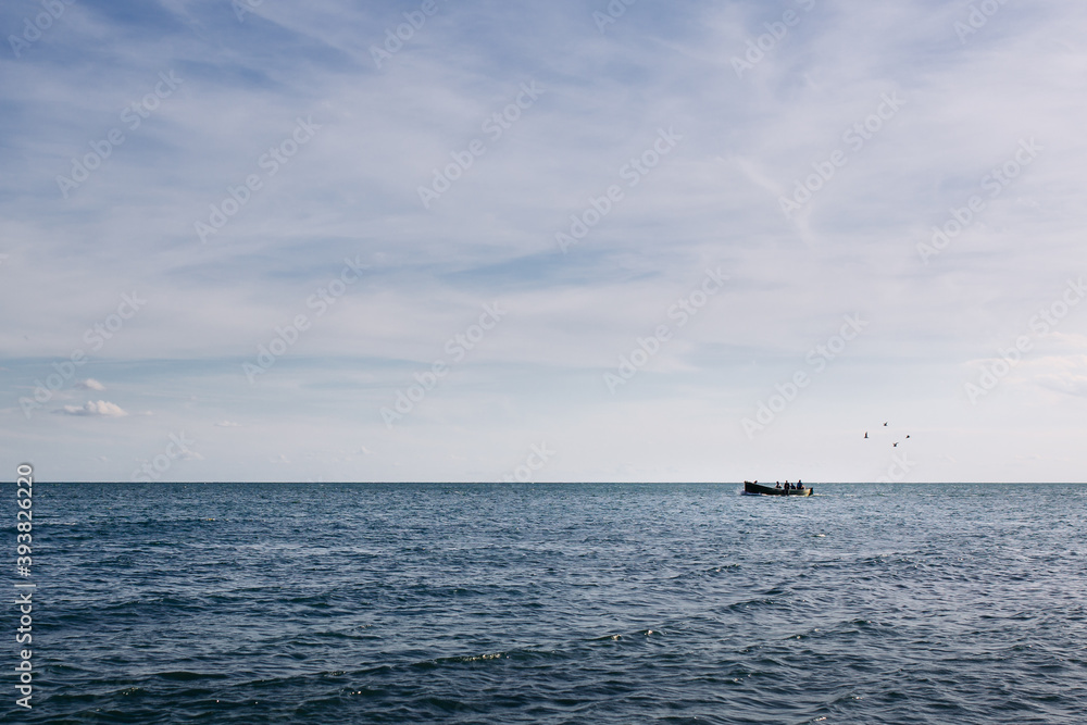 Kavarna, Bulgaria - September 2 2016: Fishing boat on the horizon followed by four birds crossing the sea