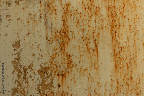 Texture of a light yellow metal plate with peeling paint, splashes and streaks of rust