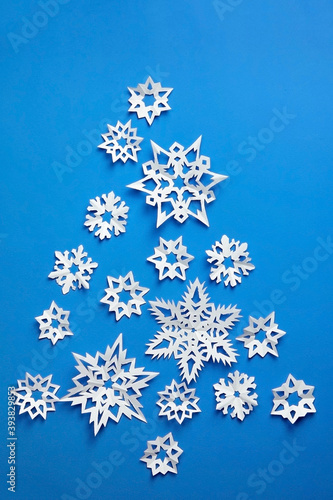 Christmas tree made from white paper snowflakes on blue