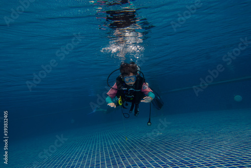 Underwater, a 10 year old boy diving in a pool with fun. This is diving for children.