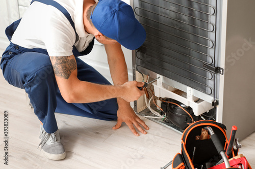 Worker repairing fridge in ...