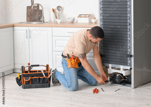Worker repairing fridge in ...