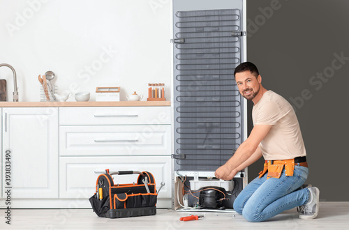 Worker repairing fridge in ...