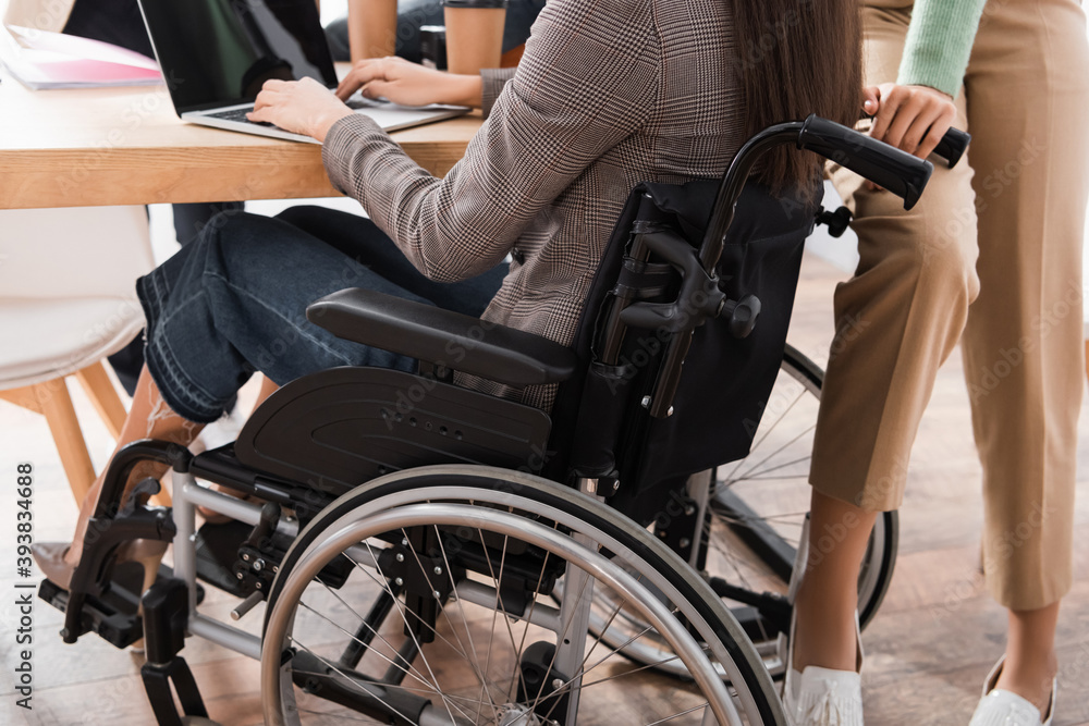 Obraz premium cropped view of hispanic handicapped businesswoman typing on laptop