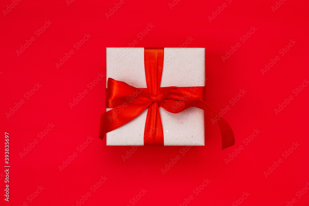 Gift box with a Christmas bow on a red background with copy space.Christmas composition. Flat lay, top view. Minimalistic style. Gift box with a Christmas bow on a red background with copy space.Christmas composition. Flat lay, top view. Minimalistic style.