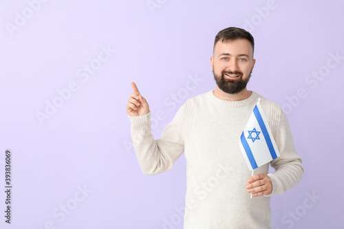 Man with the flag of Israel pointing at something on color background photo