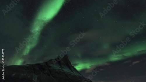 Auroras behind a sharp mountain peak, tilt up photo