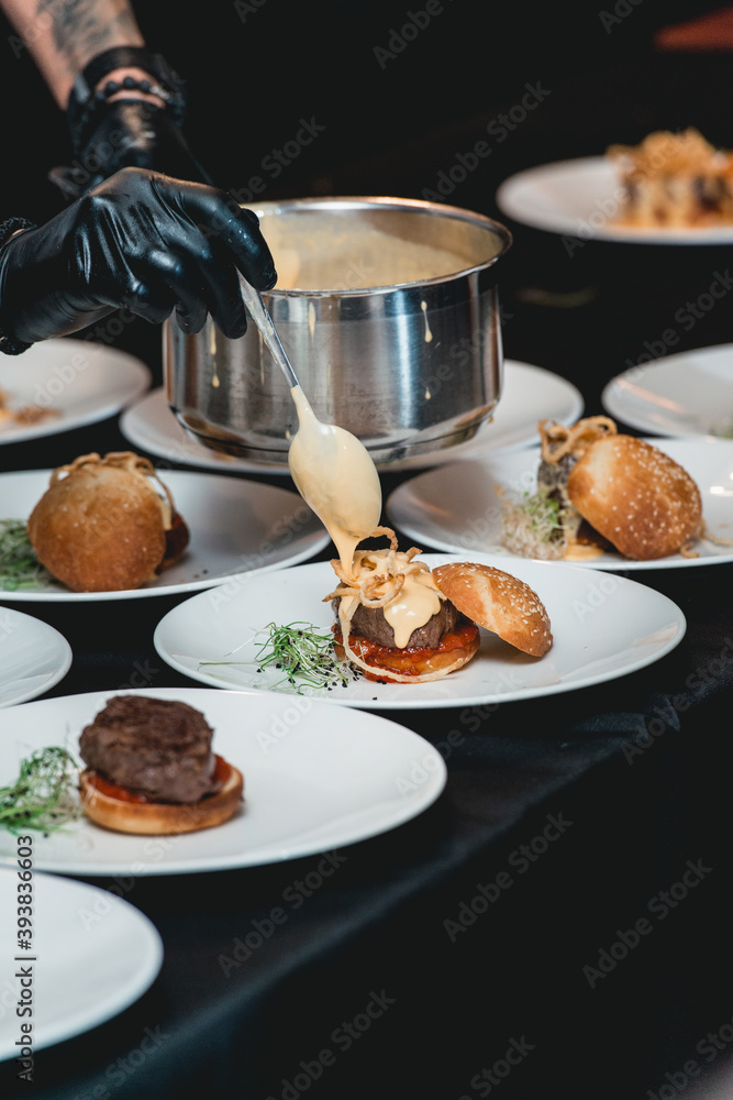 chef in a black gloves serving a burgers on the table in a restaurant