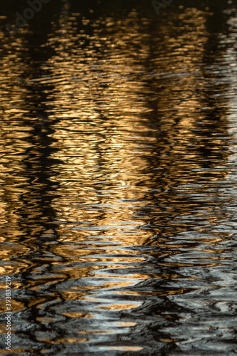 Abstract reflection in the water. Sunny day. Distorted view with ripples. Urban shot. 