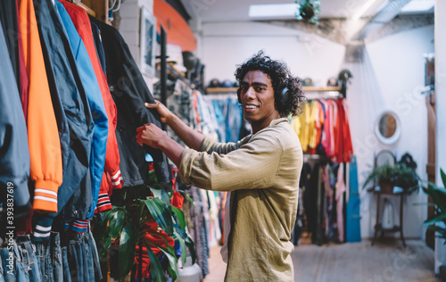 Positive young black man choosing clothes in store