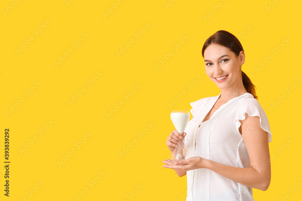 Young woman with hourglass on color background Young woman with hourglass on color background