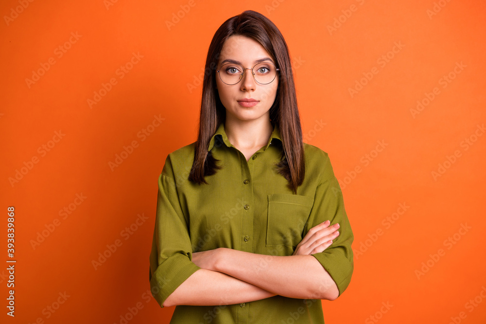 Photo portrait of female entrepreneur serious calm with crossed hands wearing glasses shirt isolated on bright orange color background Photo portrait of female entrepreneur serious calm with crossed hands wearing glasses shirt isolated on bright orange color background