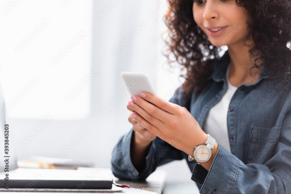 cropped view of woman smiling while using smartphone cropped view of woman smiling while using smartphone