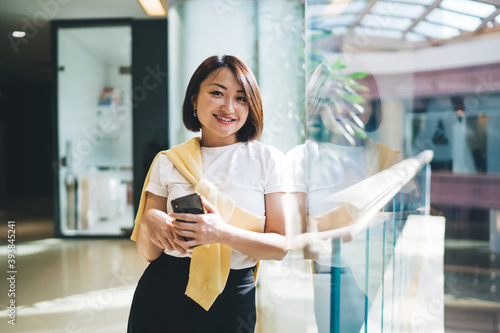 Half length portrait of beautiful asian woman in smart casual outfit enjoying work in modern office holding mobile phone, pretty female manager using smartphone for checking mail and communicating