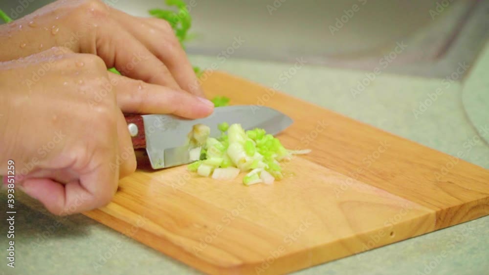 Chef slicing coriander and spring onion on a cutting board cooking table. slow motion Chef slicing coriander and spring onion on a cutting board cooking table. slow motion