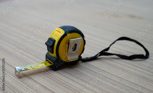 Yellow tape measure on wooden board photo