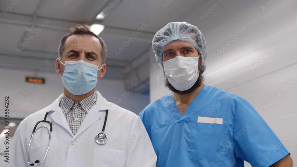 Two doctors in protective medical mask and uniform stand in emergency department hall