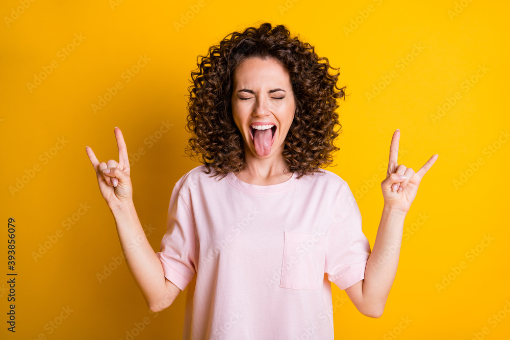 Photo portrait of crazy woman showing tongue and two rock'n'roll signs isolated on vivid yellow colored background Photo portrait of crazy woman showing tongue and two rock'n'roll signs isolated on vivid yellow colored background