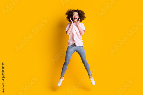 Photo portrait full body view of girl with spread legs hands near face open mouth jumping up isolated on vivid yellow colored background