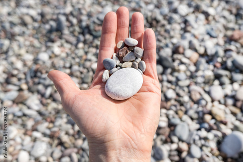 Female hand with pebble stones close-up on the background of pebble beach