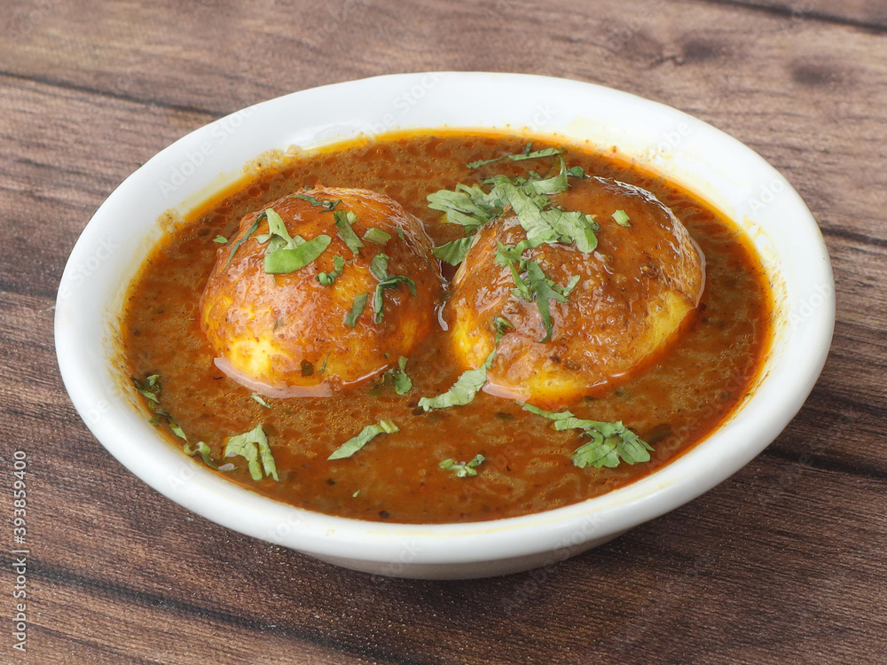 Anda Masala or Egg Curry is popular indian spicy food, served in a ceramic bowl over rustic wooden background. Selective focus Anda Masala or Egg Curry is popular indian spicy food, served in a ceramic bowl over rustic wooden background. Selective focus