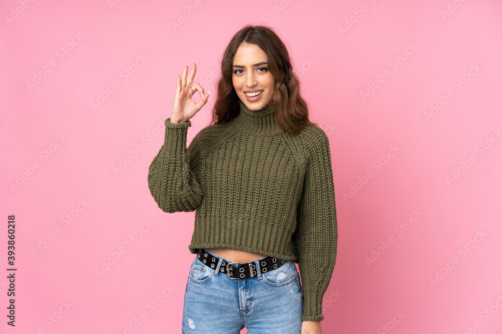 Young woman over isolated pink background showing ok sign with fingers Young woman over isolated pink background showing ok sign with fingers