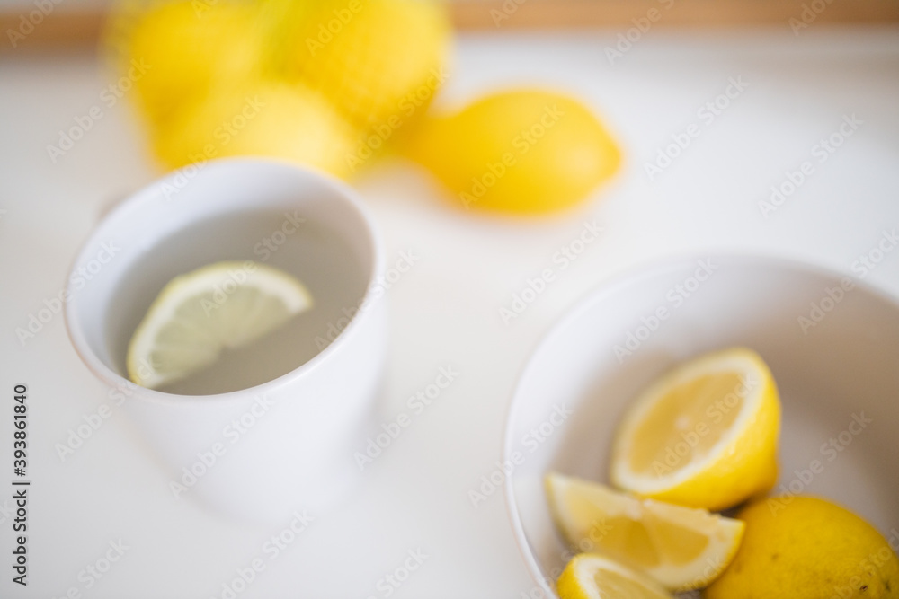 Cup of lemon tea on a white table surrounded by lemons Cup of lemon tea on a white table surrounded by lemons