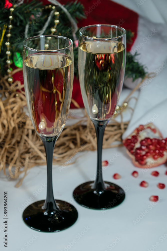 Close-up. Two glasses of champagne. Windrik Christmas background with drinks. Pomegranate fruit in the background. Close-up. Two glasses of champagne. Windrik Christmas background with drinks. Pomegranate fruit in the background.