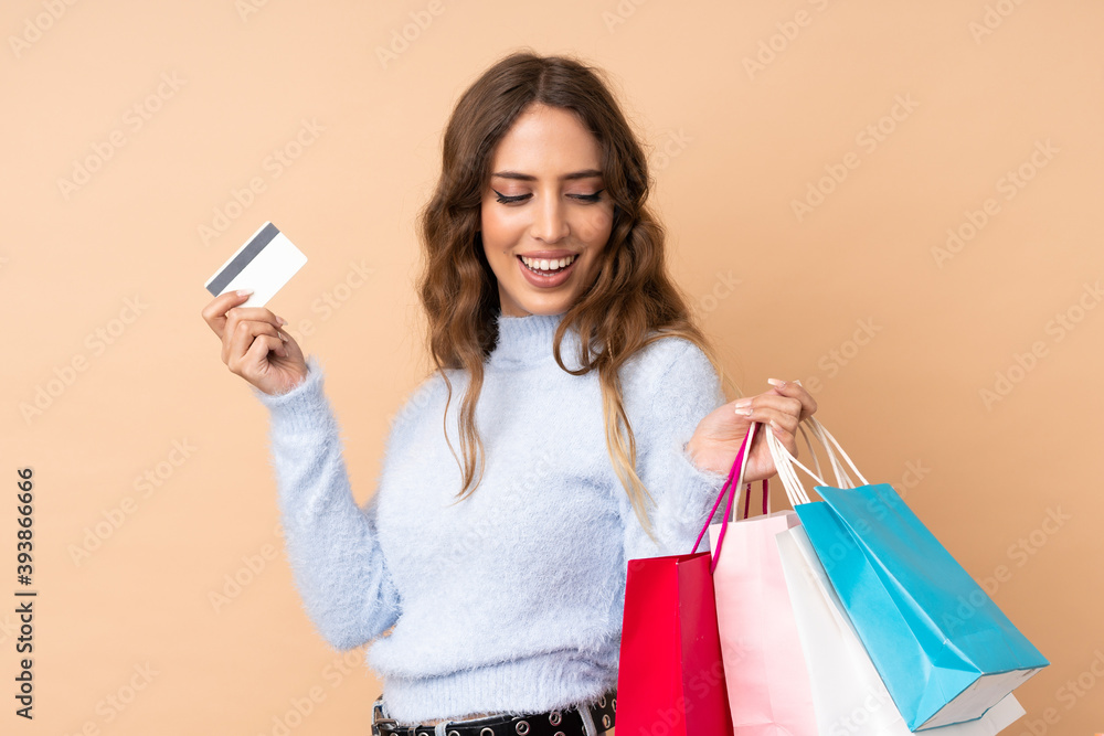 Young woman over isolated background holding shopping bags and a credit card Young woman over isolated background holding shopping bags and a credit card