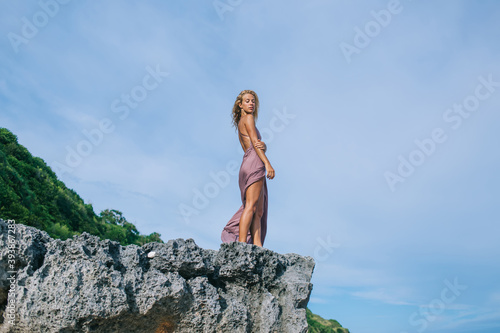 Young attractive thoughtful woman standing on rock