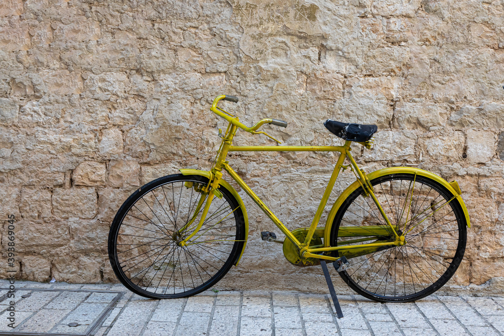 Altes gelbes Fahrrad vor einer Mauer