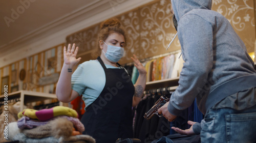 Photos Criminal in safety mask with gun robbing clothes store