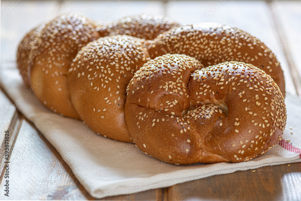 Traditional Jewish sweet Challah bread for Shabbat on a white textile on a wooden table, close up.