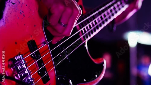 Guitarist is playing electric guitar in dark at concert stage, close-up.