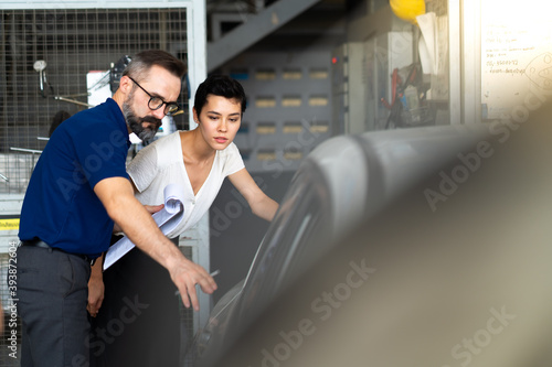 Mechanic man and woman customer check the car condition before delivery. automobile repair maintenance station garage. © NVB Stocker