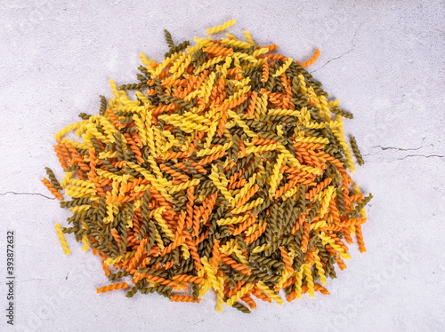 Dry pasta fusilli. Fusilli have spiral shape and yellow , green, orange color. Pasta is delicious Italian traditional food made from wheat flour like noodles.