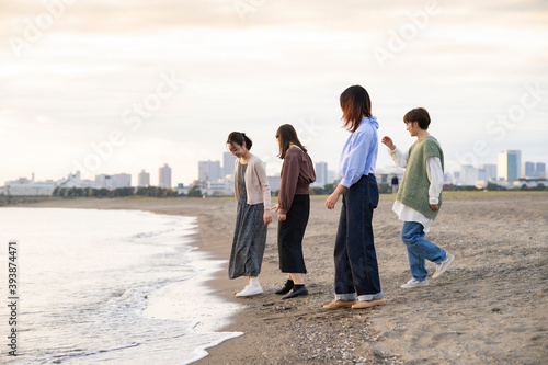 夕暮れの中、海沿いで遊ぶ若い女性4人