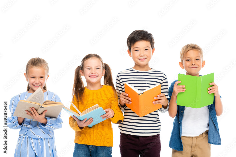 Multiethnic kids holding books while smiling at camera isolated on white Multiethnic kids holding books while smiling at camera isolated on white