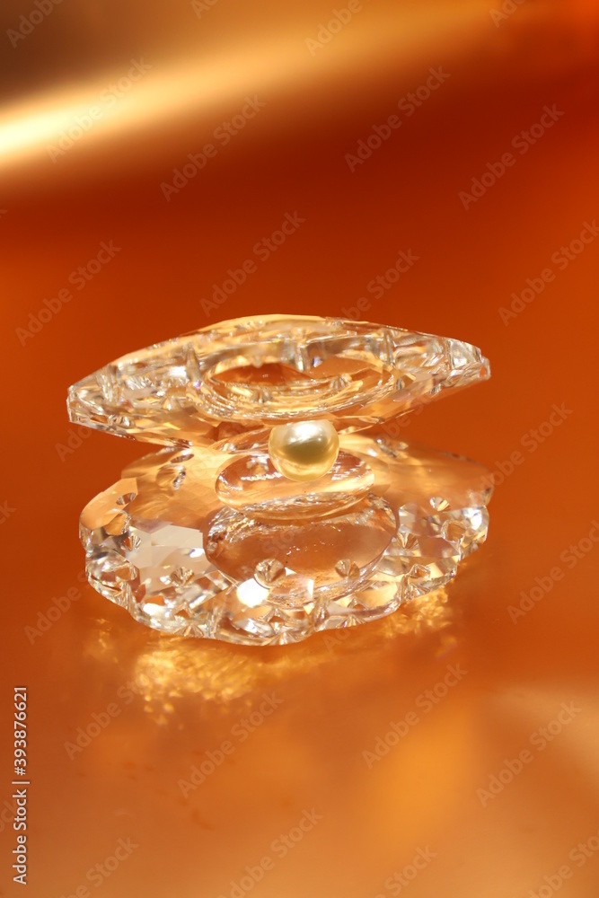 White crystal pearl in a shell show piece isolated on golden orange background with space to write your text White crystal pearl in a shell show piece isolated on golden orange background with space to write your text