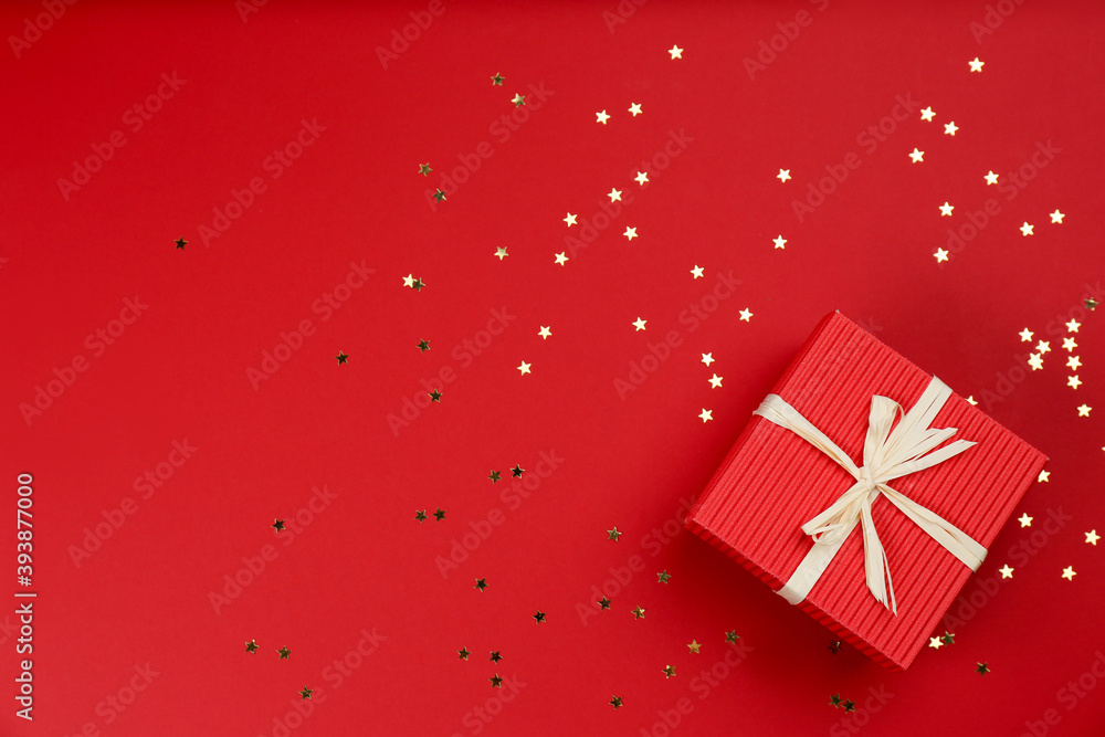 Gift box and shiny confetti on red background, top view. Space for text Gift box and shiny confetti on red background, top view. Space for text