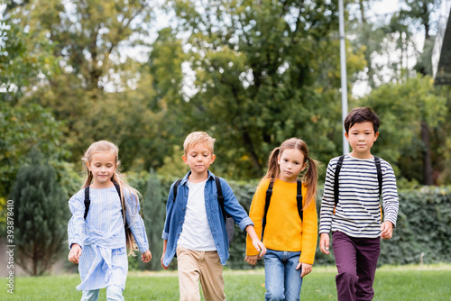 Multiethnic schoolchildren with backpacks walking outdoors